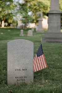 american flag beside a gray tombstone of a veteran